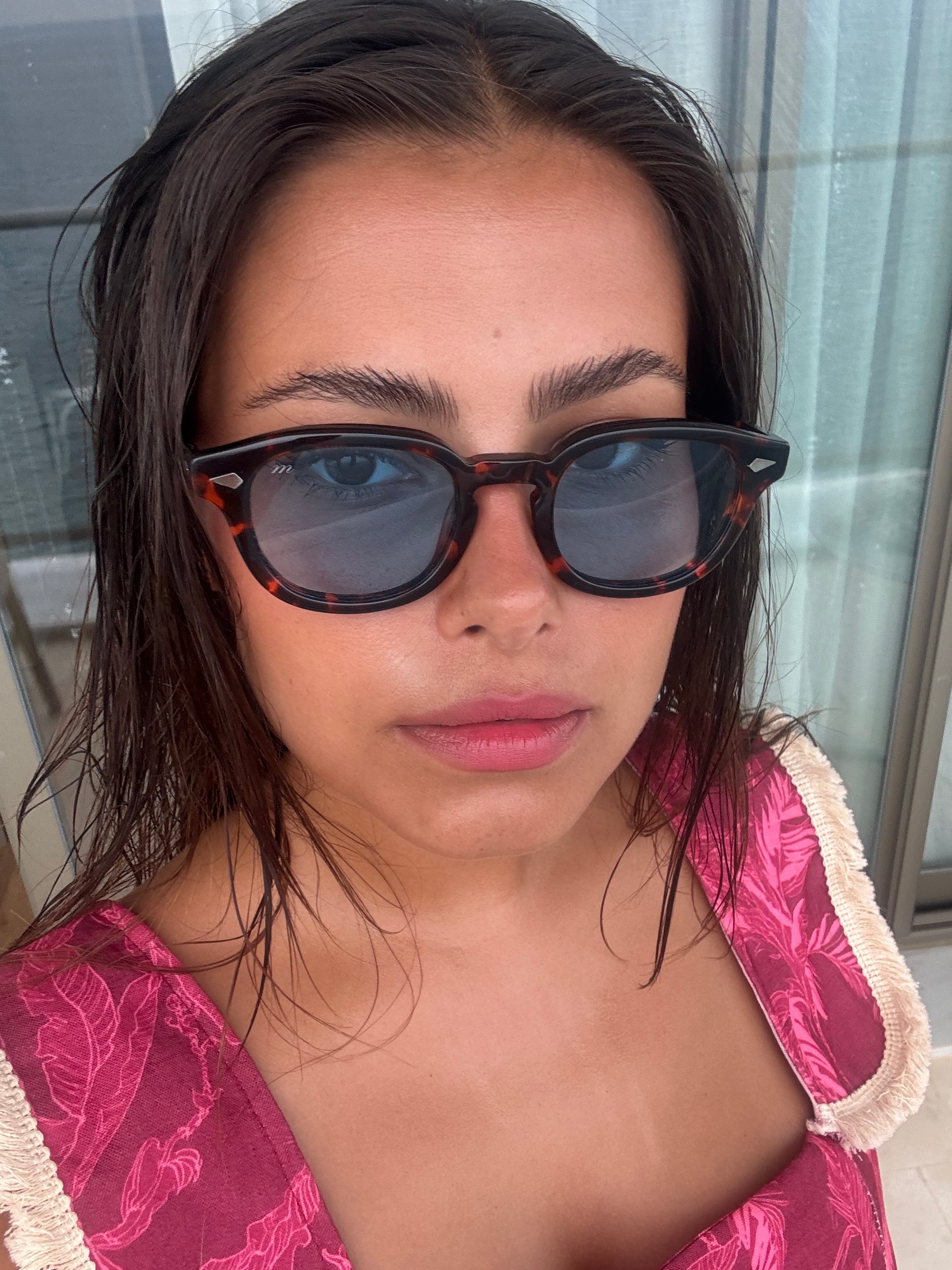Woman wearing Misu Solène 
sunglasses and a pink top with floral patterns.